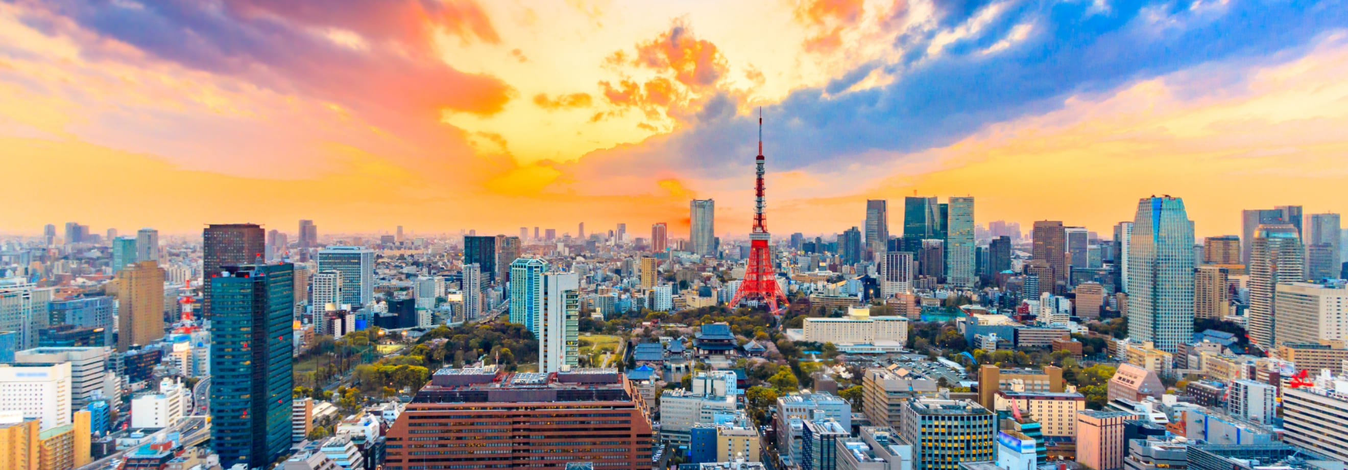 夕焼け空で中央に東京タワーが見えて周りには高層ビルやマンションなどが見渡せる画像